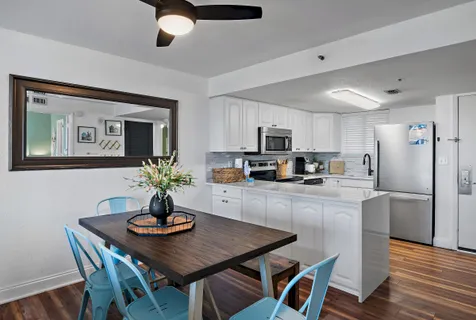 a kitchen with stainless steel appliances granite countertop a dining table chairs and refrigerator