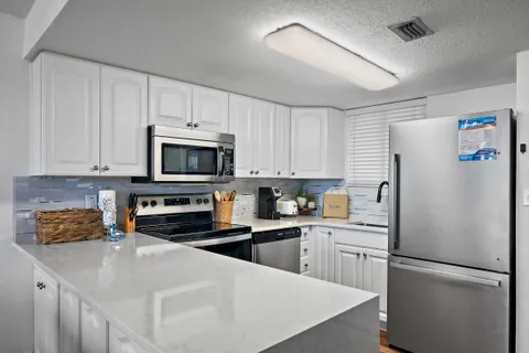a kitchen with stainless steel appliances a refrigerator a stove a sink and white cabinets