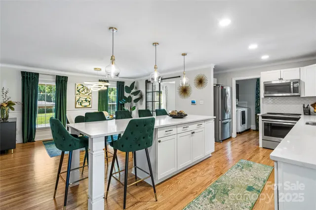 a kitchen with stainless steel appliances kitchen island a table and chairs in it