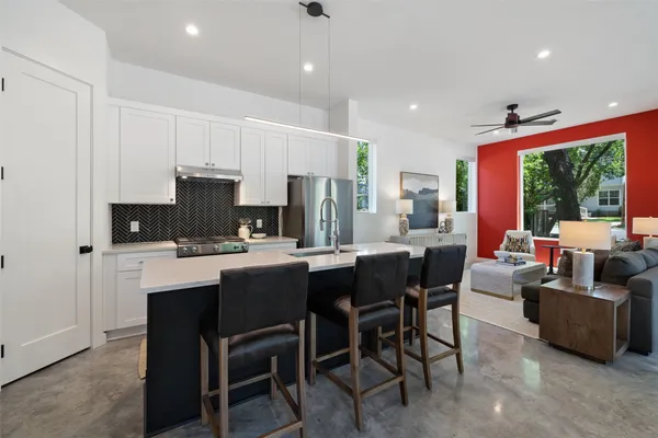 a kitchen with stainless steel appliances granite countertop a stove a refrigerator a kitchen island a sink dishwasher a dining table and chairs with wooden floor