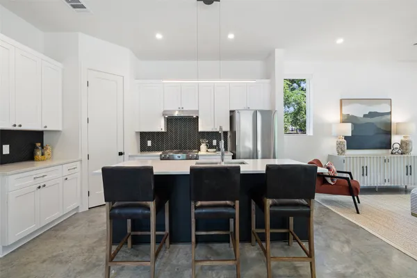 a kitchen with stainless steel appliances a dining table chairs and a refrigerator