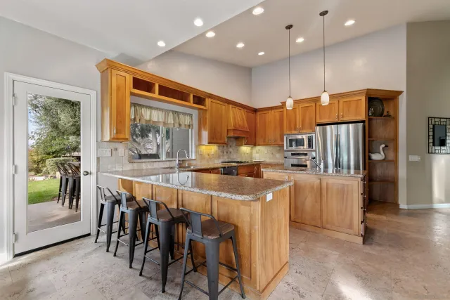 a kitchen with stainless steel appliances granite countertop a refrigerator and a stove top oven