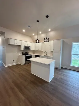 a large kitchen with kitchen island a sink a center island stainless steel appliances and a window
