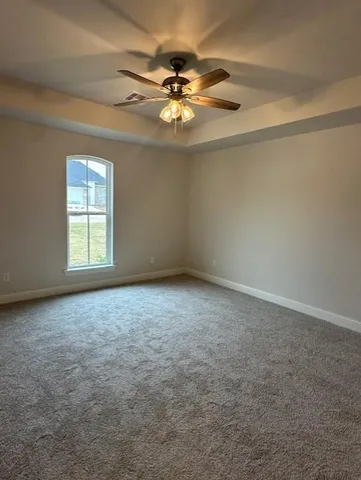 an empty room with a ceiling fan and window