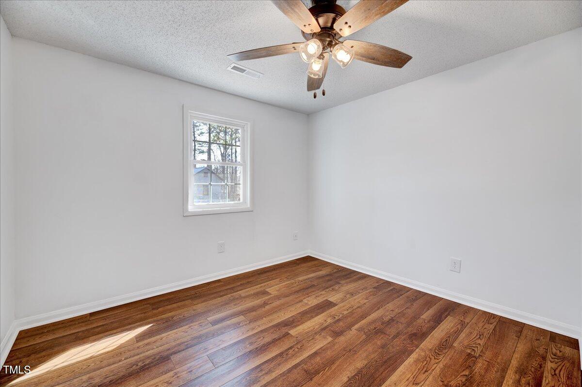 103 Allendale Road Four Oaks, NC 27524 - Photo 22 of 44 an empty room with wooden floor chandelier fan and windows