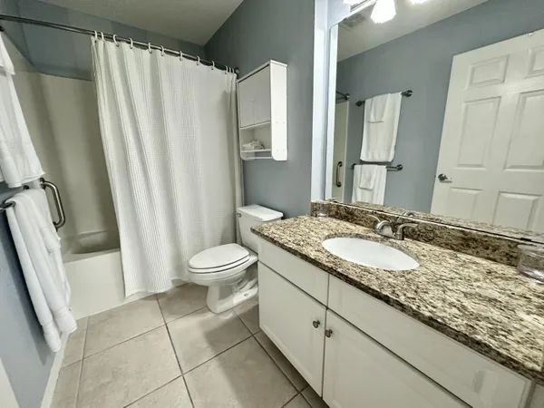 a en suite bathroom with a granite countertop sink and a mirror