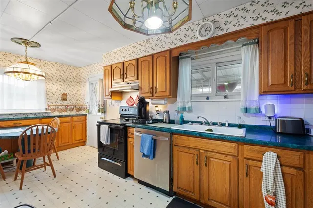 a kitchen with stainless steel appliances granite countertop wooden cabinets a sink a stove a dining table and chairs