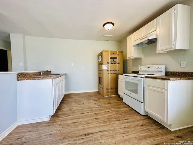 a kitchen with cabinets and wooden floor
