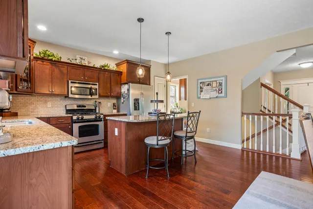 a kitchen with stainless steel appliances granite countertop a stove top oven a sink a dining table and chairs with wooden floor