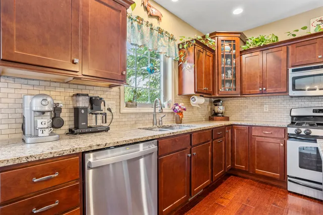 a kitchen with granite countertop stainless steel appliances a sink window and cabinets