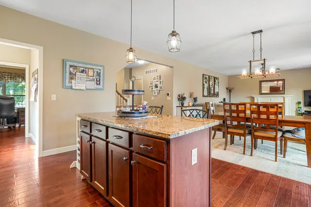 a kitchen with stainless steel appliances kitchen island granite countertop a table chairs and a wooden floor
