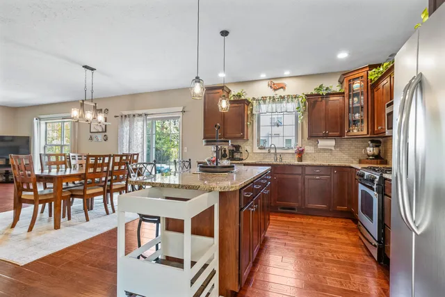 a kitchen with stainless steel appliances kitchen island granite countertop a table chairs and a refrigerator