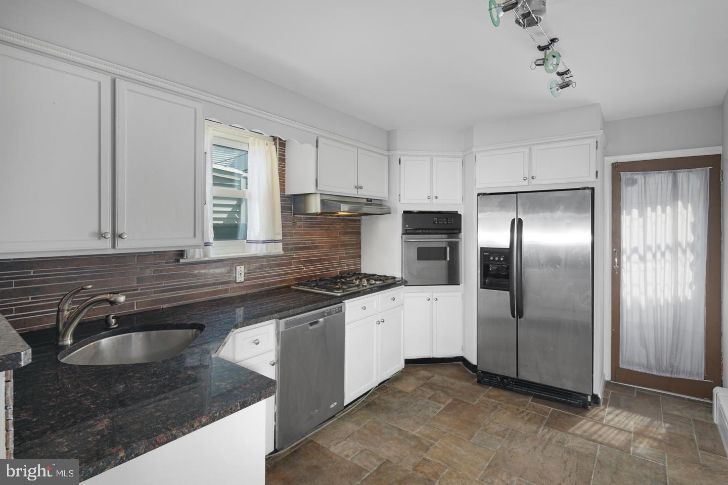 a kitchen with granite countertop a sink stainless steel appliances and window