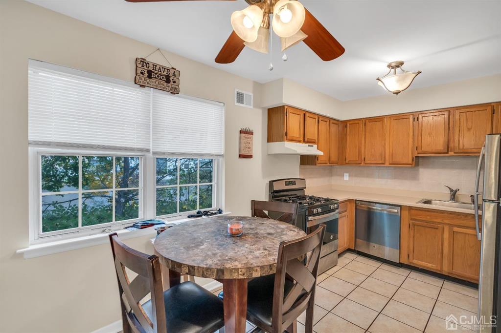 32 Hanover Square Middlesex, NJ 08846 - Photo 8 of 25 a kitchen with stainless steel appliances granite countertop wooden cabinets a stove a sink a dining table and chairs