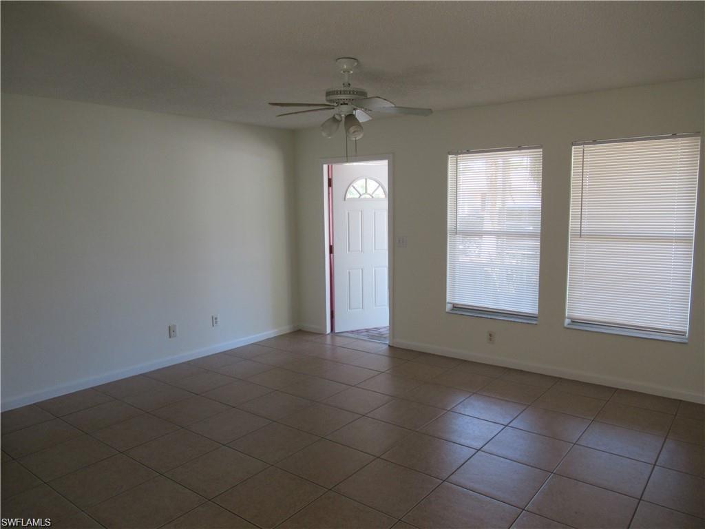 18608 Sebring Road Fort Myers, FL 33967 - Photo 2 of 13 an empty room with a chandelier fan and windows
