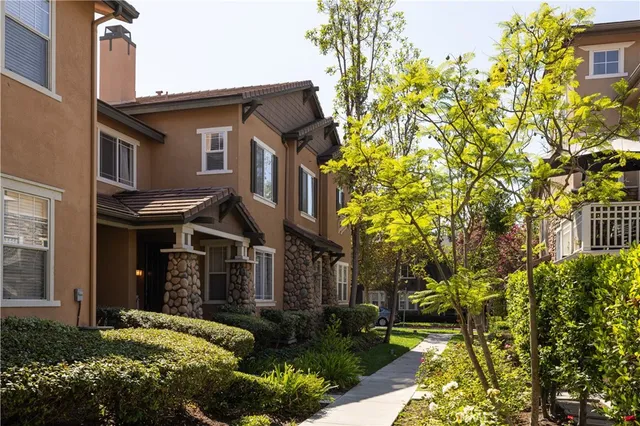 a view of a brick house with a yard and plants