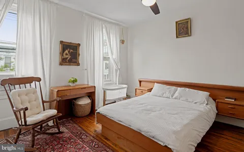 a bedroom with a bed a chair and next to a window
