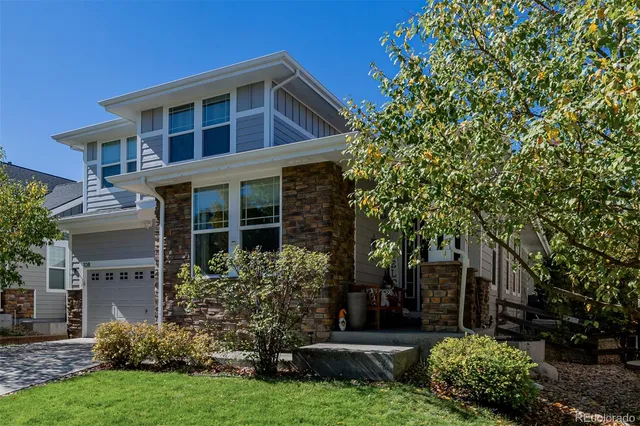 a view of a house with brick walls and a yard with plants and trees