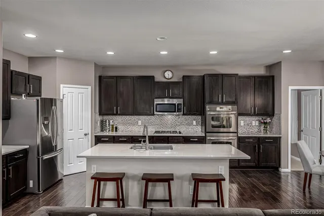a kitchen with kitchen island a refrigerator and a stove top oven