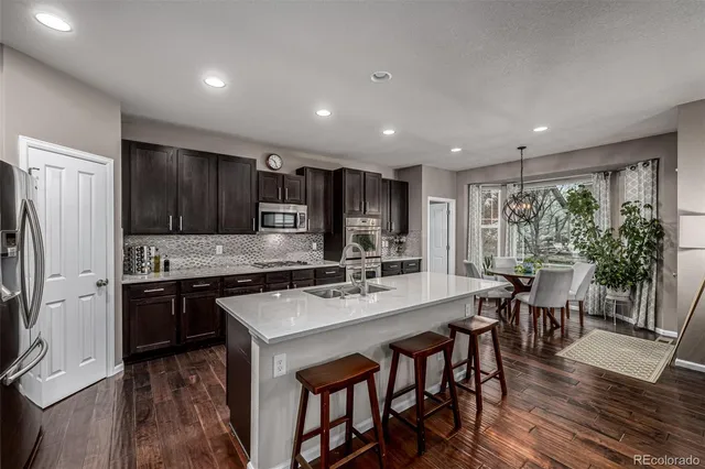 a kitchen with stainless steel appliances granite countertop a stove a refrigerator a kitchen island a table and chairs