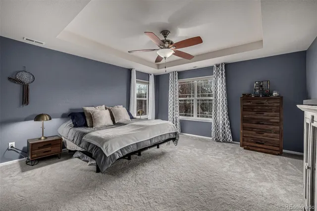 a spacious bedroom with a bed a dresser and a chandelier