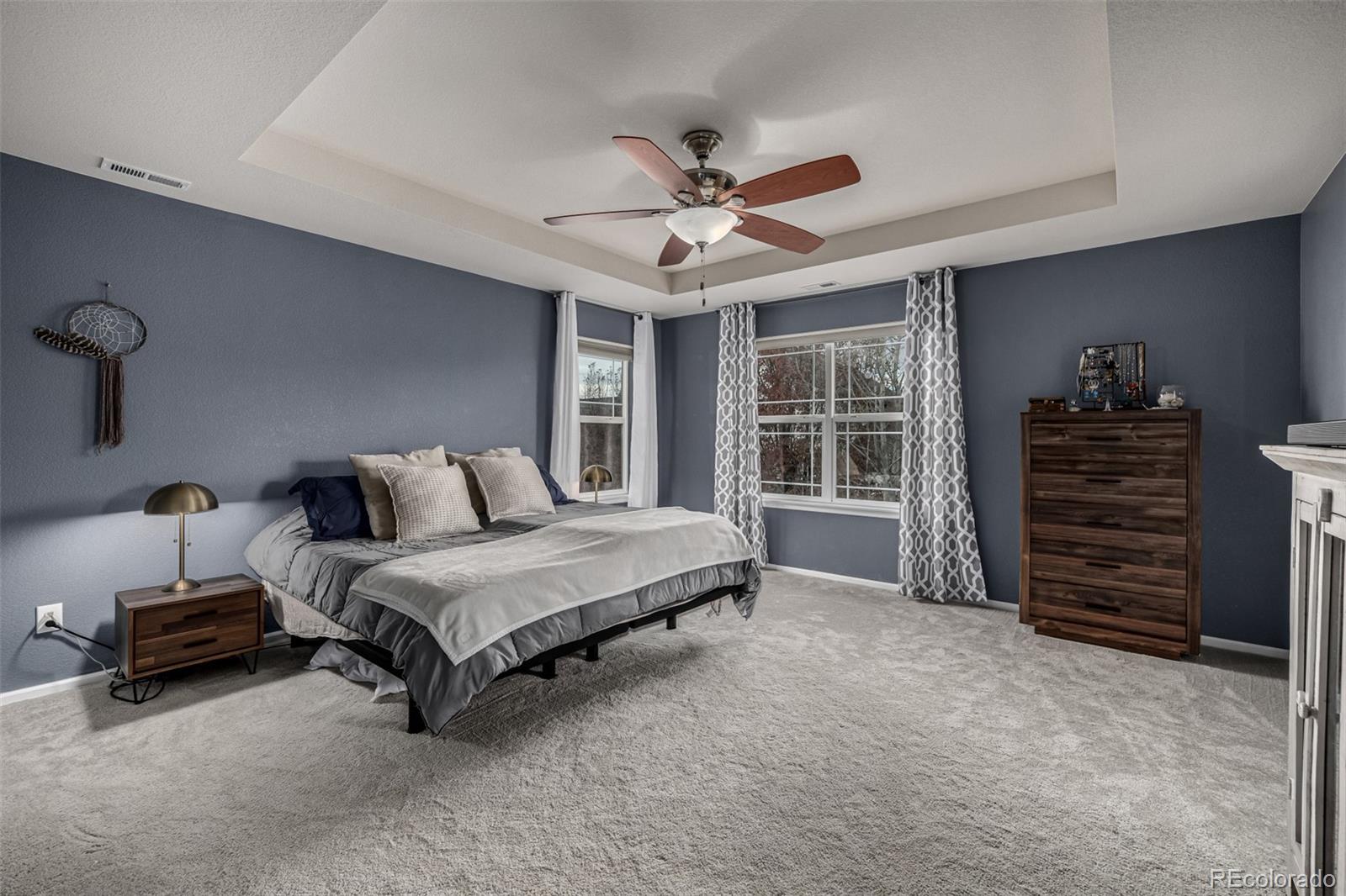 1138 Mircos Street Erie, CO 80516 - Photo 22 of 46 a spacious bedroom with a bed a dresser and a chandelier