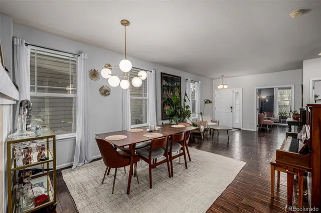 a dining room with wooden floor a chandelier a wooden table and chairs