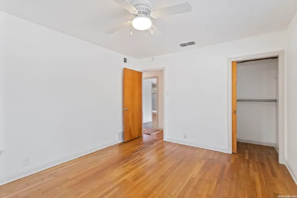 an empty room with wooden floor and a ceiling fan