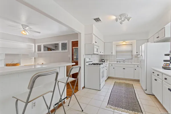 a kitchen with a stove a refrigerator and white cabinets