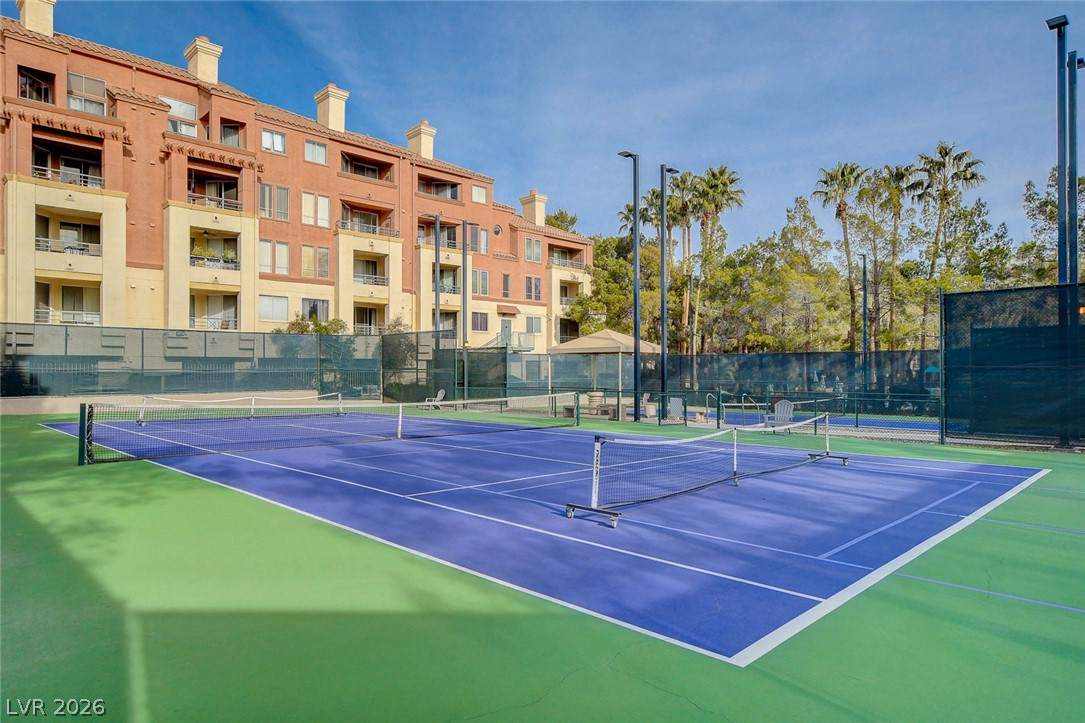 230 East Flamingo Road, Unit 106 Las Vegas, NV 89169 - Photo 55 of 66 Serve up fun on this well-maintained tennis court, set against a backdrop of mature trees and a modern multi-story building.