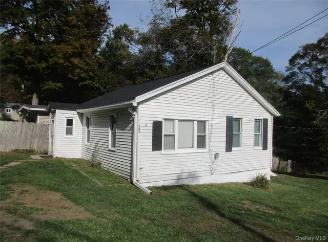 a view of a white house next to a yard with big trees