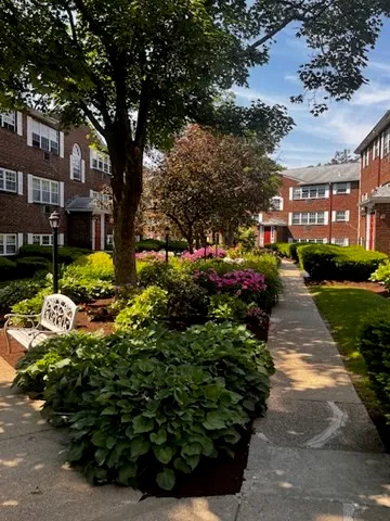 a front view of a multi story residential apartment building with yard and green space