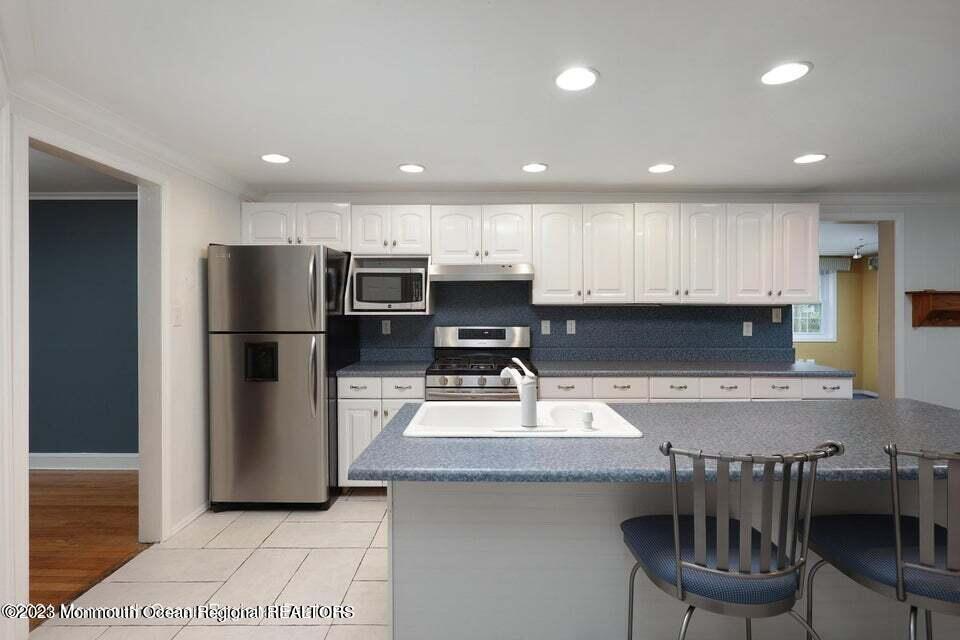 219 Elmwood Road Oakhurst, NJ 07755 - Photo 2 of 4 a kitchen with refrigerator and chairs