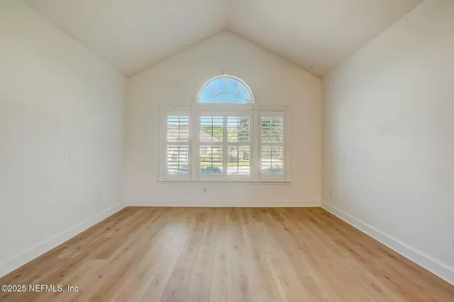 a kitchen with stainless steel appliances granite countertop a stove a sink a refrigerator and white cabinets with wooden floor