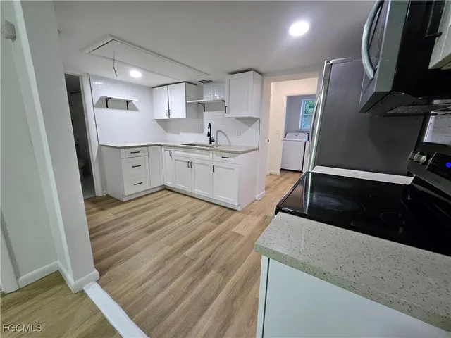 a kitchen with a sink a refrigerator a window and cabinets