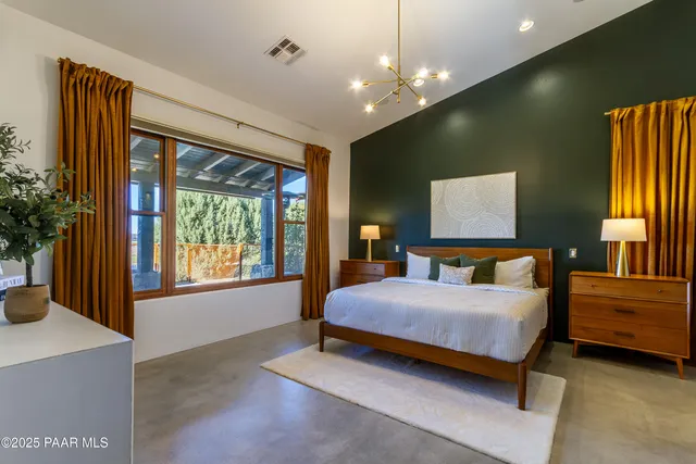 a bedroom with a bed chandelier and a window