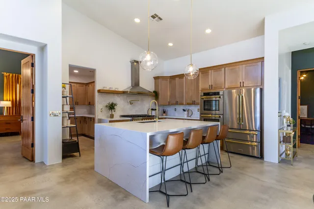 a large kitchen with stainless steel appliances kitchen island granite countertop a refrigerator and a stove top oven