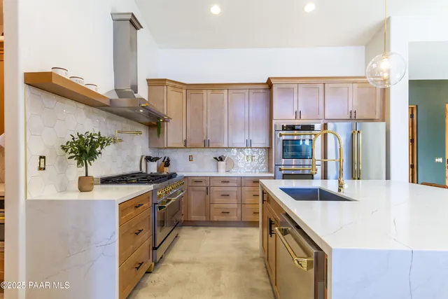 a kitchen with stainless steel appliances granite countertop a sink a stove and a refrigerator