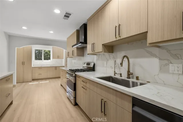 a kitchen with stainless steel appliances granite countertop a sink a stove and a refrigerator