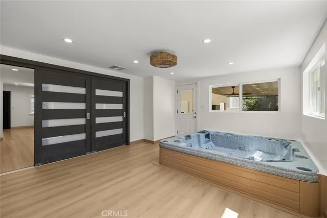 a spacious bedroom with a bed and a dresser with wooden floor