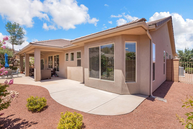 1587 Whitestone Drive St. George, UT 84790 - Photo 22 of 36 Exterior stucco finish with a covered patio, extensive concrete patio, and a low-maintenance landscape featuring crushed rock and plantings