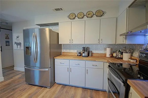 a kitchen with stainless steel appliances granite countertop a refrigerator a stove and a sink