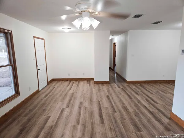 a view of an empty room with wooden floor and a window