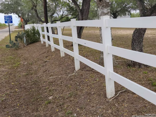 a view of a dry yard with wooden fence