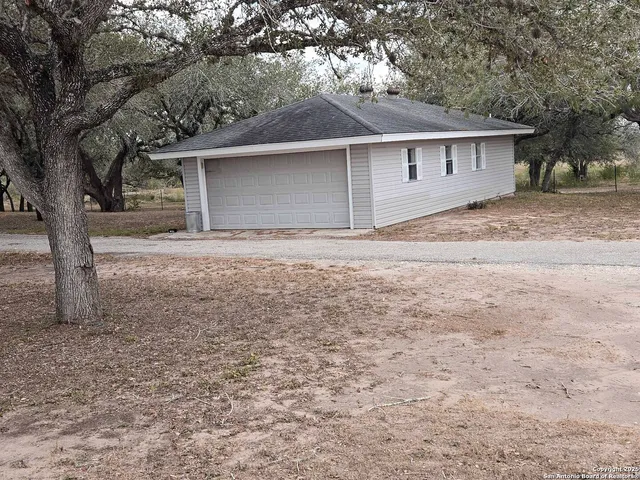 a view of a house with a yard and large tree