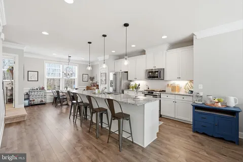 a large kitchen with cabinets chairs and wooden floor