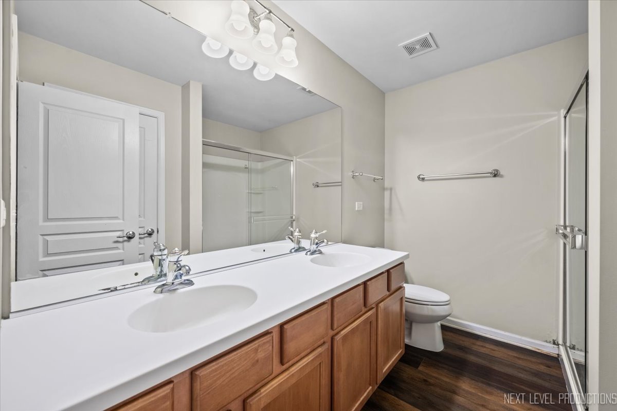 643 Hawley Drive, Unit 643 Oswego, IL 60543 - Photo 20 of 27 a bathroom with a sink a toilet and a large mirror