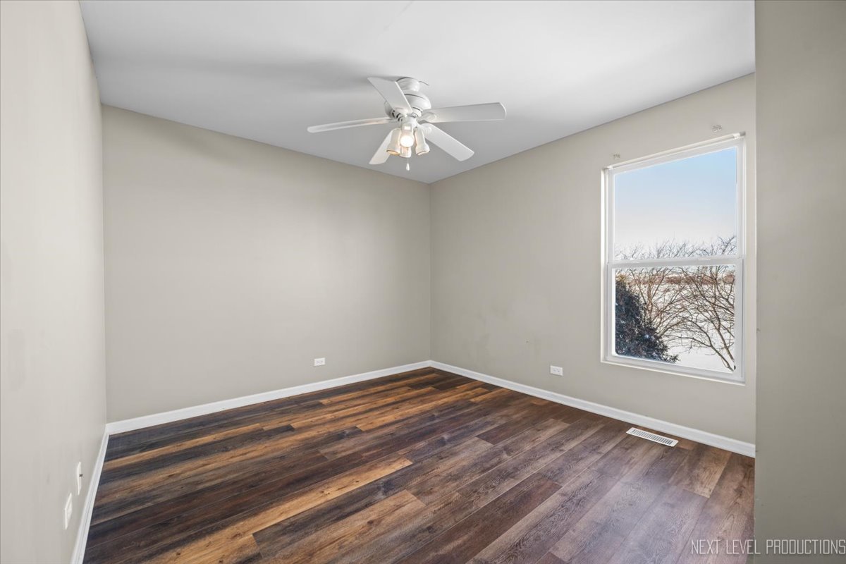 643 Hawley Drive, Unit 643 Oswego, IL 60543 - Photo 22 of 27 an empty room with wooden floor chandelier fan and windows