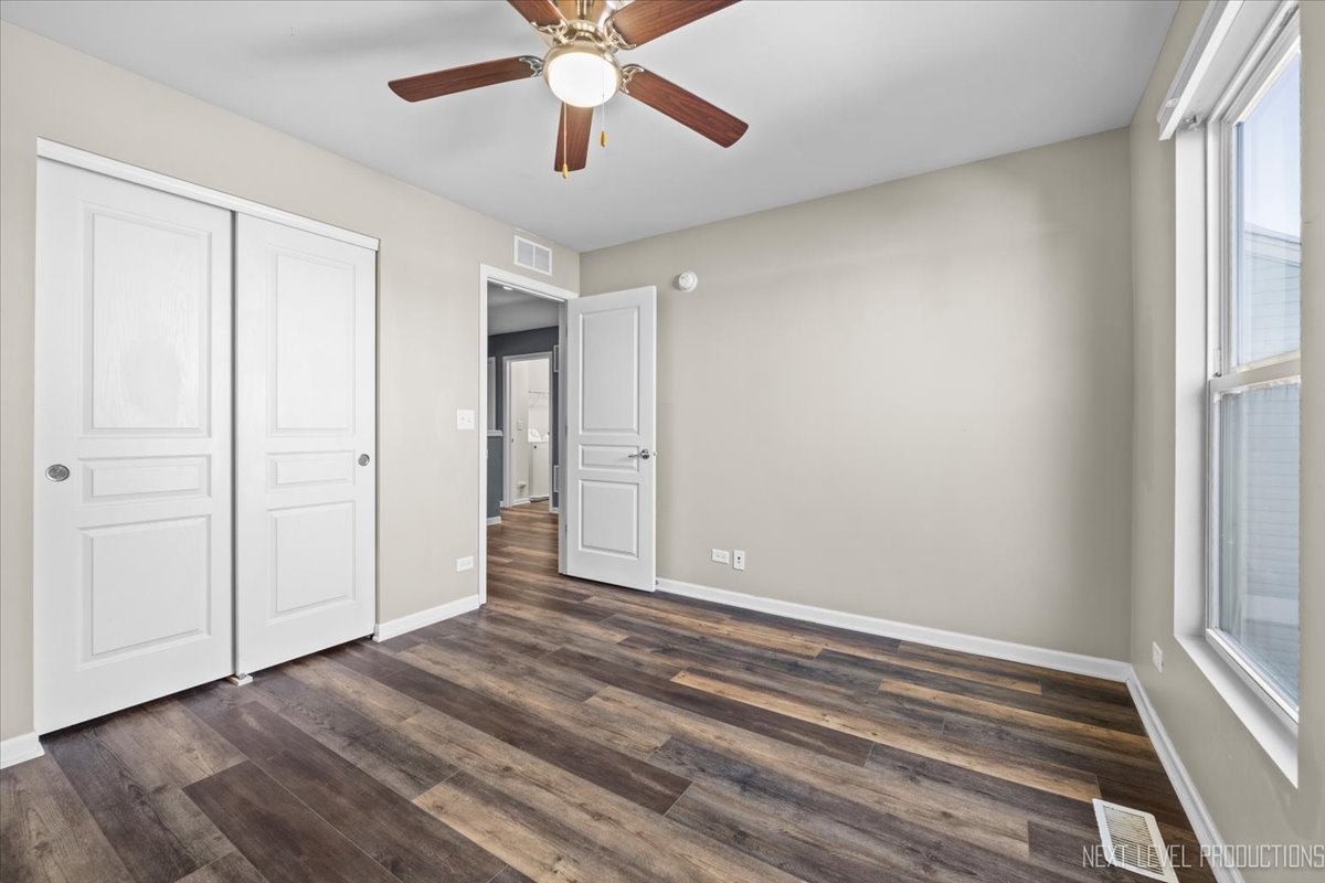 643 Hawley Drive, Unit 643 Oswego, IL 60543 - Photo 23 of 27 an empty room with wooden floor chandelier fan and windows