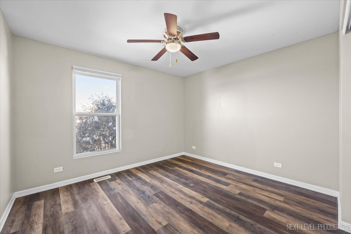 643 Hawley Drive, Unit 643 Oswego, IL 60543 - Photo 24 of 27 an empty room with wooden floor ceiling fan and windows